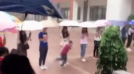 Chinese teachers hold umbrellas for schoolchildren during downpour