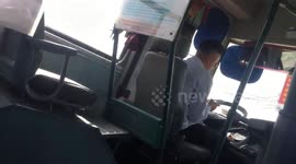 The bus driver uses the phone for messaging while he driving on the road