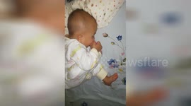 Adorable baby licks toes while sleeping