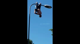 Swedish man juggles while hanging from lamp post