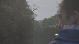 Man in a boat cruising down the river in the Kinabatangan Rainforest, Sabah Borneo Malaysia