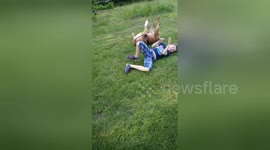 They're inseparable! Boy and his dog mimic each other by rolling in the grass