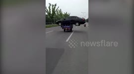 Three-wheeler transports entire sedan on busy main road