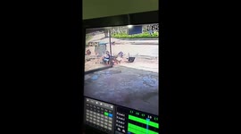 Two men riding a motorbike crash with fruit street shop and the house