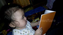 A one years old baby in Bukittinggi,west Sumatera,Indonesia pretends to read in front of her daddy to show that she can do it better.