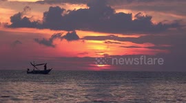 Ocean sunrise and fishing boats on a beach in Thailand.