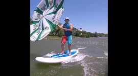 Russian man whizzes across pond using umbrella as sail