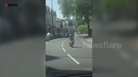 Moped rider wheelies down the wrong side of busy main road