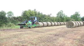 An Irish farmer wraps bales of hay in black plastic.