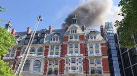 Firefighter inspects Mandarin Oriental hotel fire while on top of tall ladder