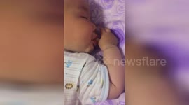 Cute baby licks thumb while sleeping