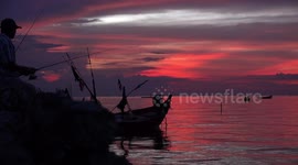 Fishing after sunset, under an amber sky in Thailand.