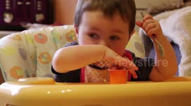 A cute messy kid eats a yogurt.