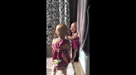 Giggling twins playing with shower curtain