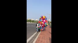 Balloon salesman struggles in high winds on Vietnam road