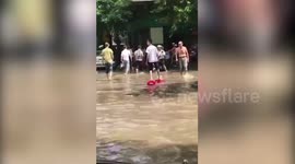Man ties plastic stools to his feet to cross flooded street