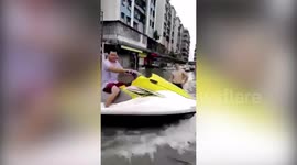 Man jet skis across flooded road in China