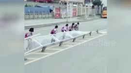 Diligent Chinese pupils lift up central reservation blown down on road