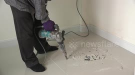 Drilling holes in new tiles looking for a water leak.