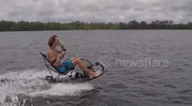 Man drinks beer while sitting on a lawn chair attached to a jetsurf board