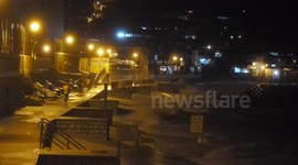 Men stand in waves caused by Typhoon Kalmaegi