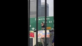 Man on freeway sign brings traffic to a standstill in downtown Los Angeles