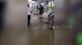 Commuters struggle to walk in flooded metro after heavy rainstorm