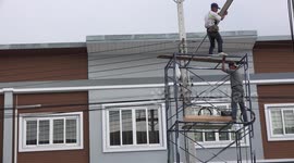 Electricians replace a street lamp, without safety harness or hard hats.
