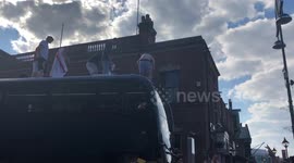 Football fans help each other on top of bus after England’s quarter final win