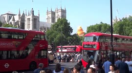 Trump Baby Blimp seen from Westminster tube station above double-decker buses on the bridge