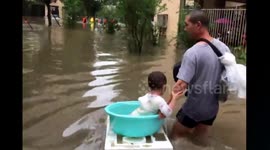 Dad uses homemade 'boat' to transport son in floods