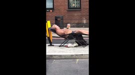 Man reclines on deck chair with a drink in the middle of London traffic