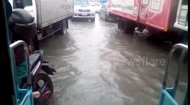 Cars drive through knee-deep waters as rainstorm hits Manila