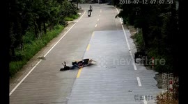 Scooter rider continues looking at phone in middle of road after being knocked over