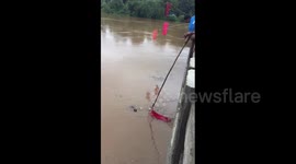 Residents in southern India rush to fish coconuts from flooded river