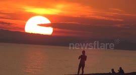 Beachgoers enjoy a warm autumn sunset in Brighton, UK