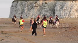 Pony and riders galloping on the Beach in Joss Bay Kent by jim connor young girls and boys riding there pony's on the beach in the sea with the white cliffs behind and the blue sea in front
