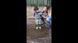 Boy with Cerebral palsy, laughs with joy as he splashes in puddle for the first time