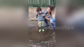 Boy with Cerebral palsy, laughs with joy as he splashes in puddle for the first time
