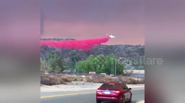 Firefighting plane drop trail of bright red retardant against apocalyptic sky