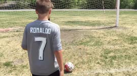 Boy kicks soccer ball at his friend.