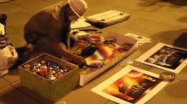 Street artist spray painting on paper and selling it to the public