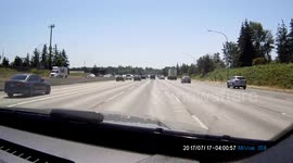 Seattle Freeway chaos when driver decides to make a late exit and spins out of control then re-enters the interstate at high speed crossing lanes with vehicles swerving and breaking to avoid a collision.