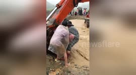 Rescuers use excavator to help villagers over flooded river