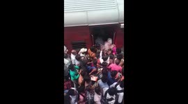 Crowds of people climb aboard train in New Delhi
