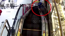 Boy jams head between escalator handrail and wall
