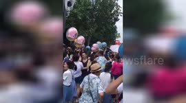 Tourists grab balloons for sale at Shanghai Disneyland