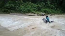 Motorcycle with rider washing away in flooded drain in India