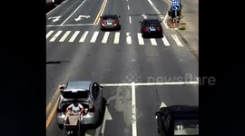 Woman drags wheelbarrow behind moving car