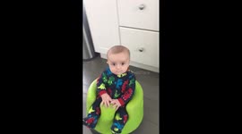 Cute US baby rides tiny robot vacuum cleaner around kitchen floor
